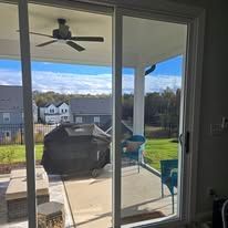 A sliding glass door leading to a patio with a grill and a ceiling fan.