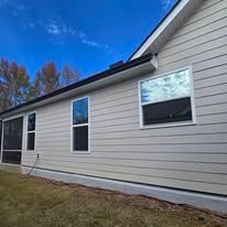 The side of a house with a lot of windows and a screened in porch.