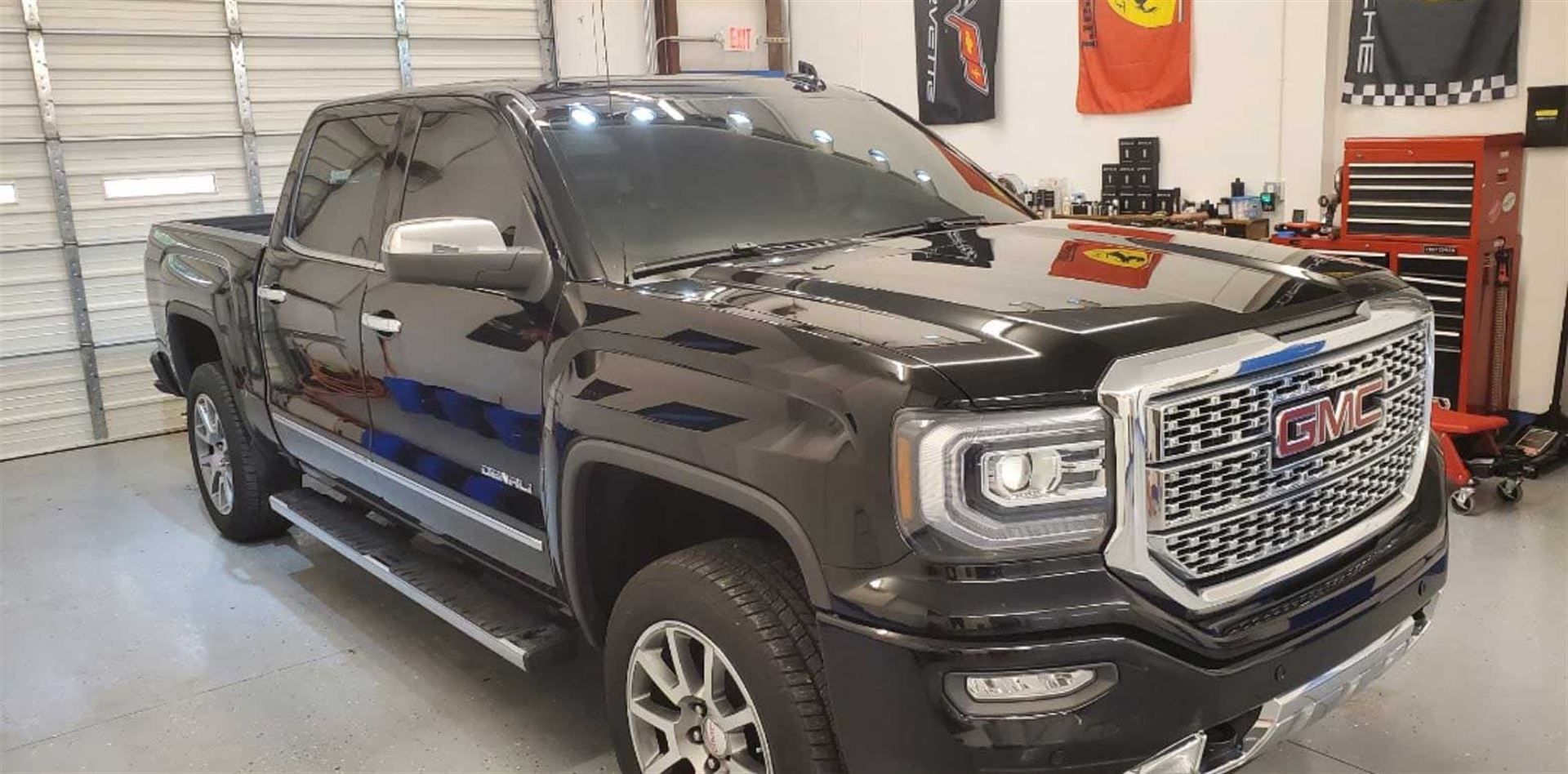 A black gmc sierra pickup truck is parked in a garage.