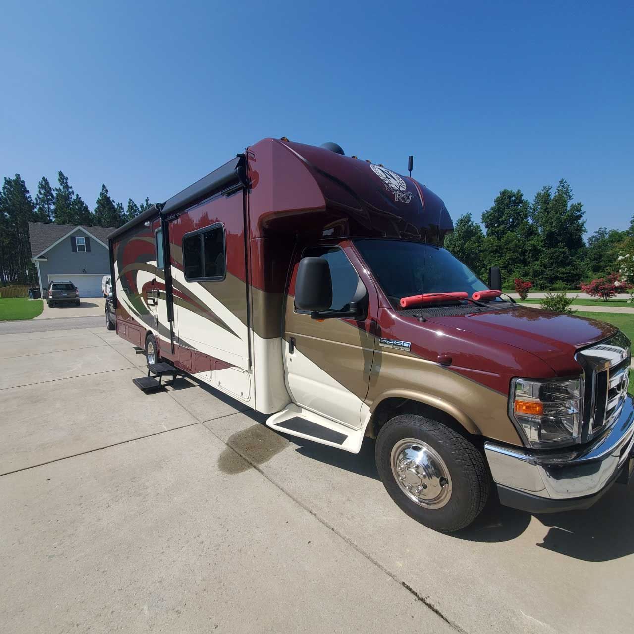 A brown and white rv is parked in a driveway