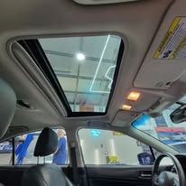 A car with a sunroof is parked in a garage.