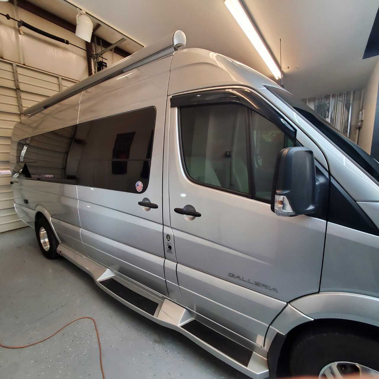 A large silver van is parked in a garage