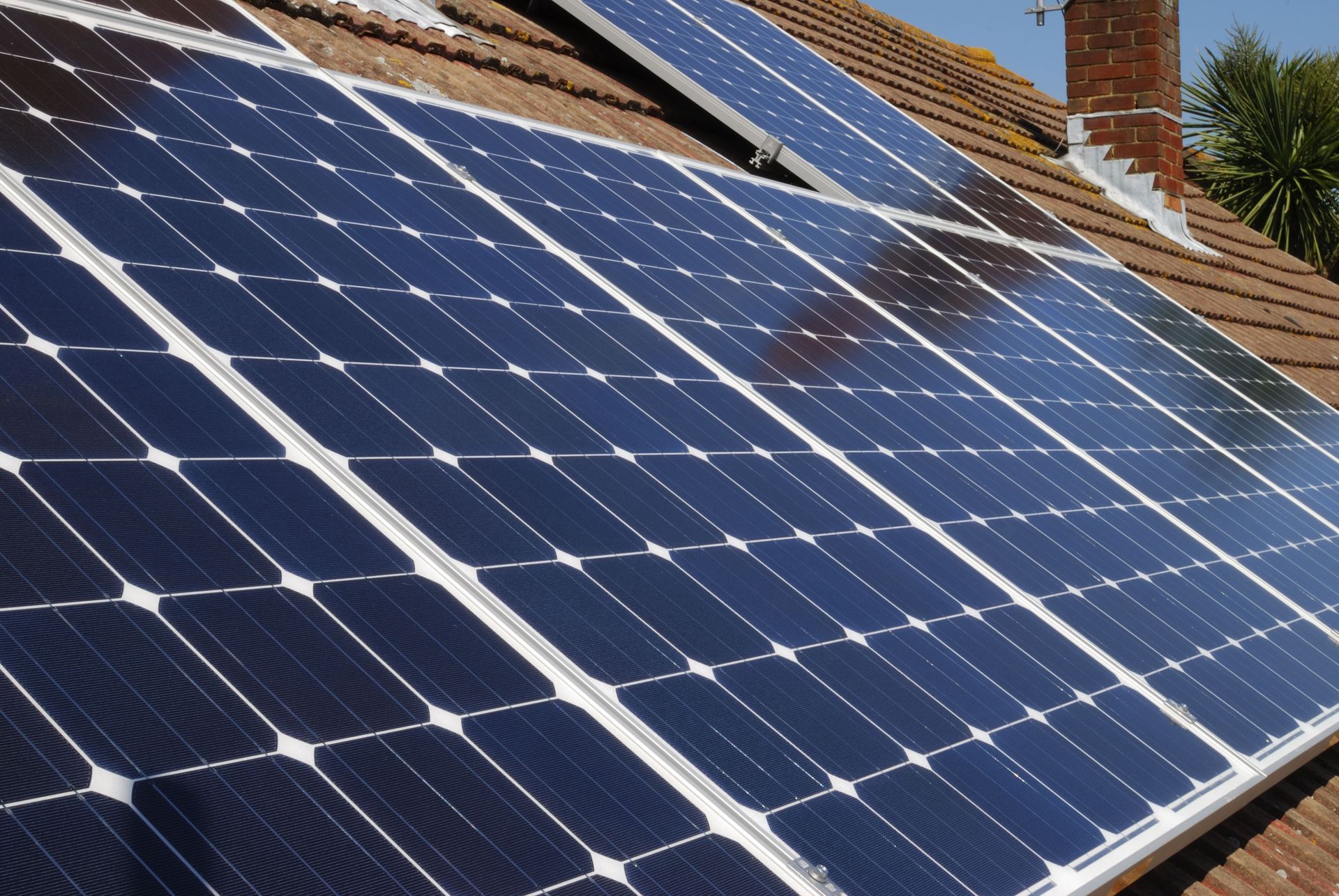 Solar panels installed on a brown tiled roof, capturing sunlight.