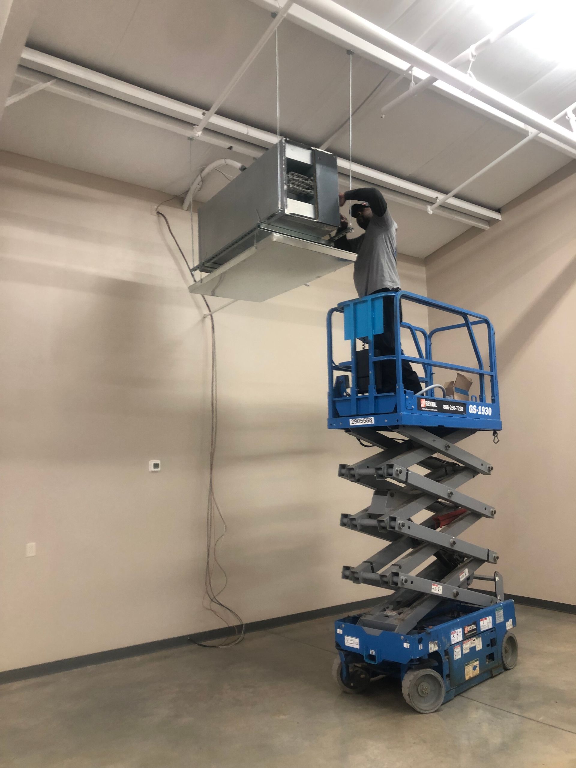 a man is standing on a scissor lift in a room