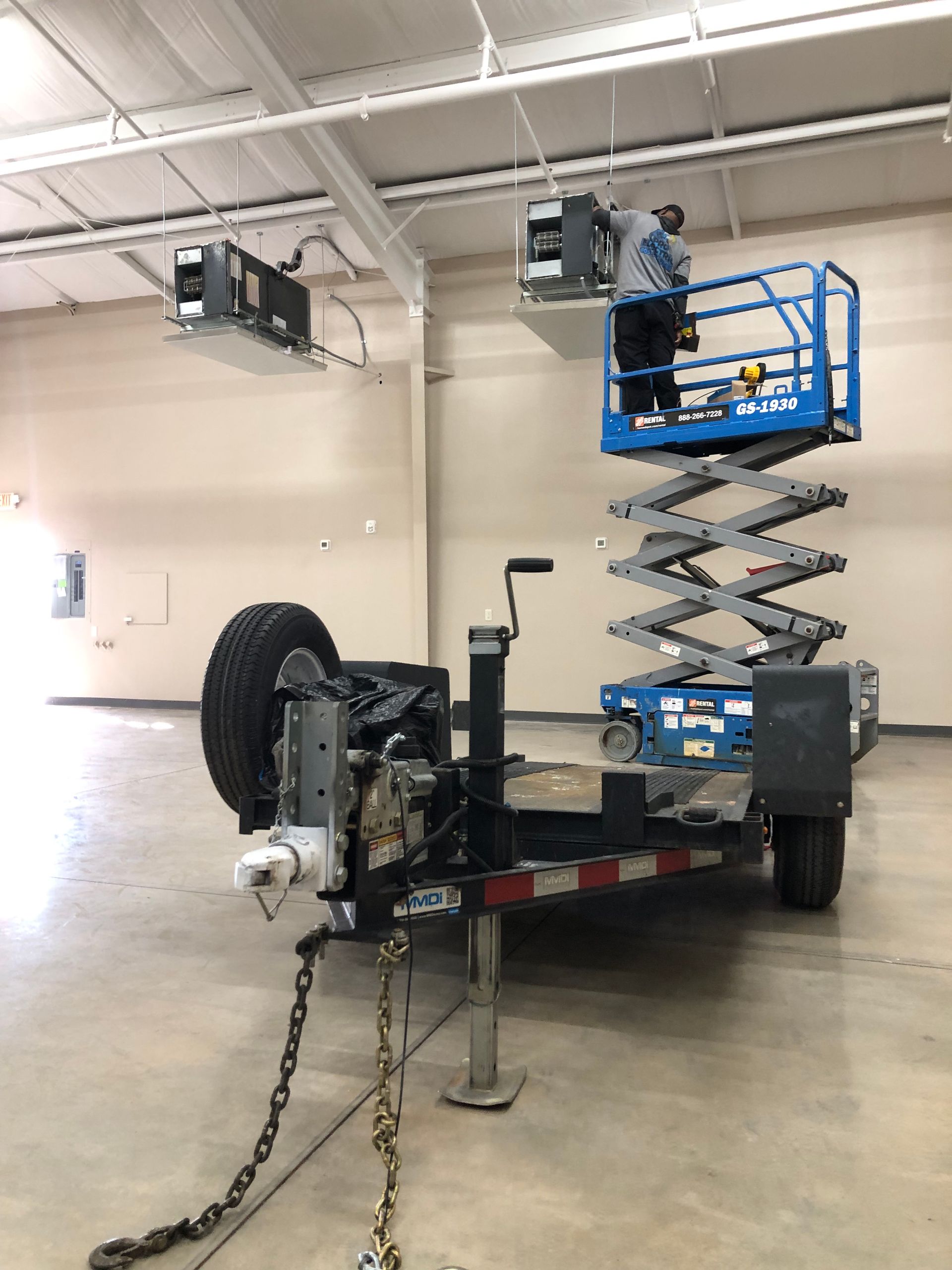 a man is working on a scissor lift on a trailer