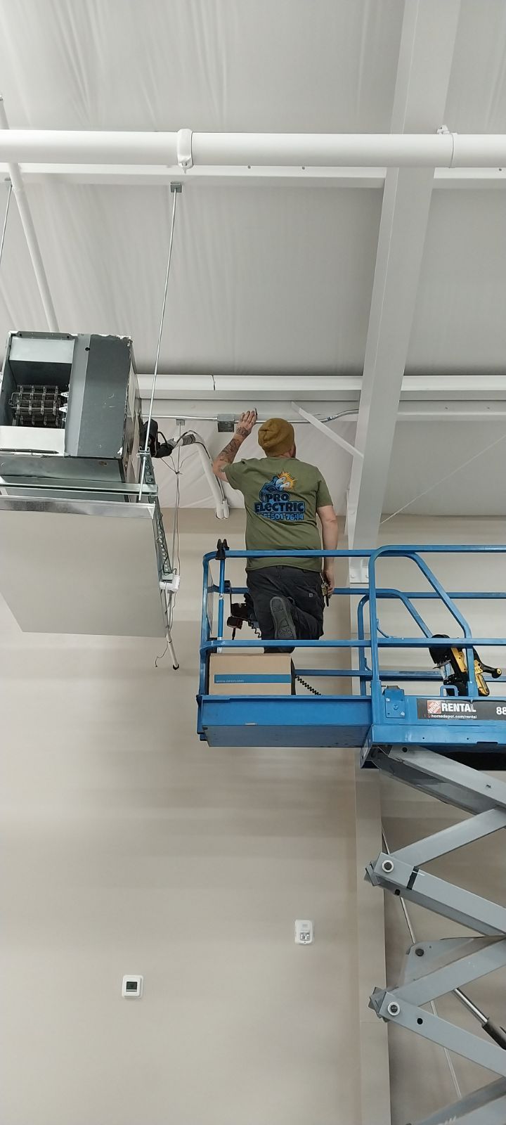 a man is standing on a scissor lift working on a ceiling