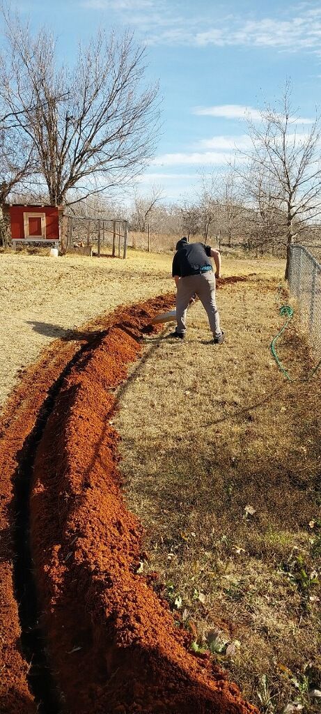 a man is digging a trench in the dirt in a field