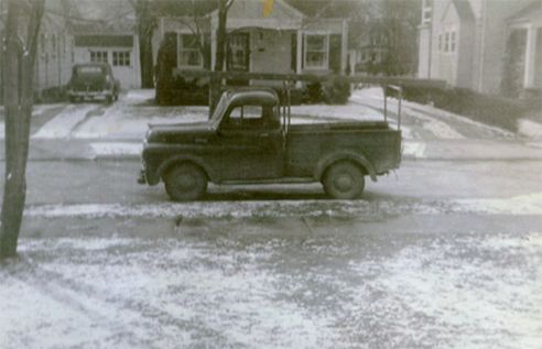 A black and white photo of a truck parked on the side of the road.