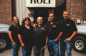 The Holt family is posing for a picture in front of their building.