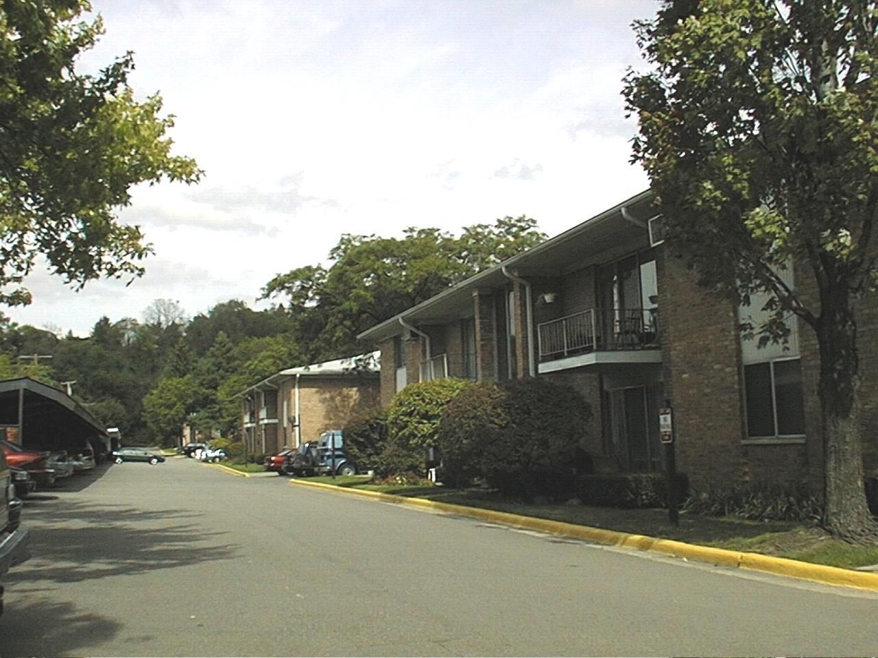 A row of apartment buildings with cars parked in front of them