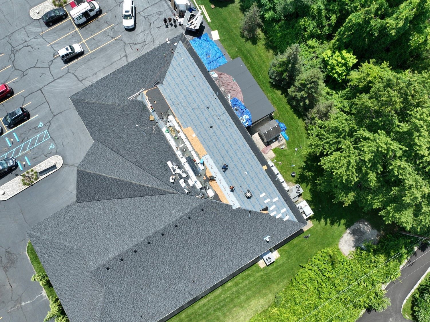 An aerial view of a roof being repaired in a parking lot.