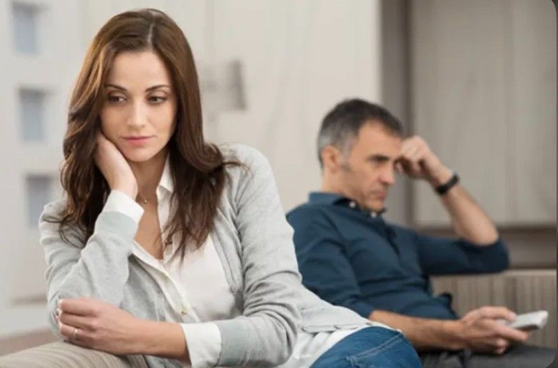 A woman is sitting on a couch next to a man.
