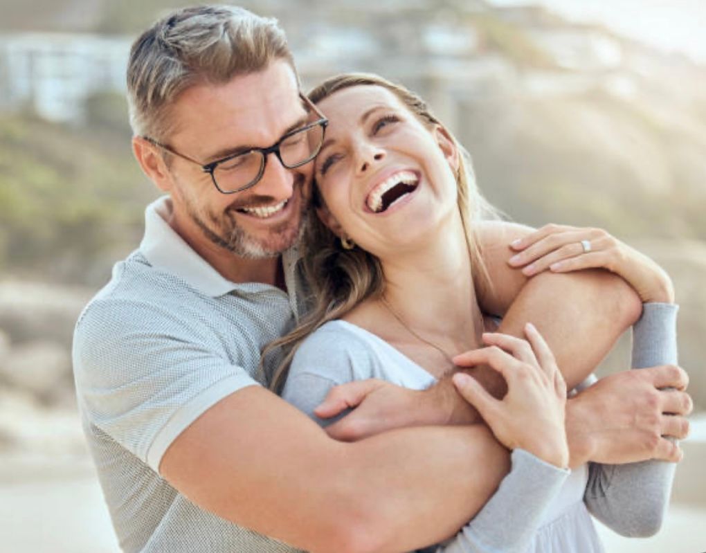 A man and a woman are hugging each other and laughing.