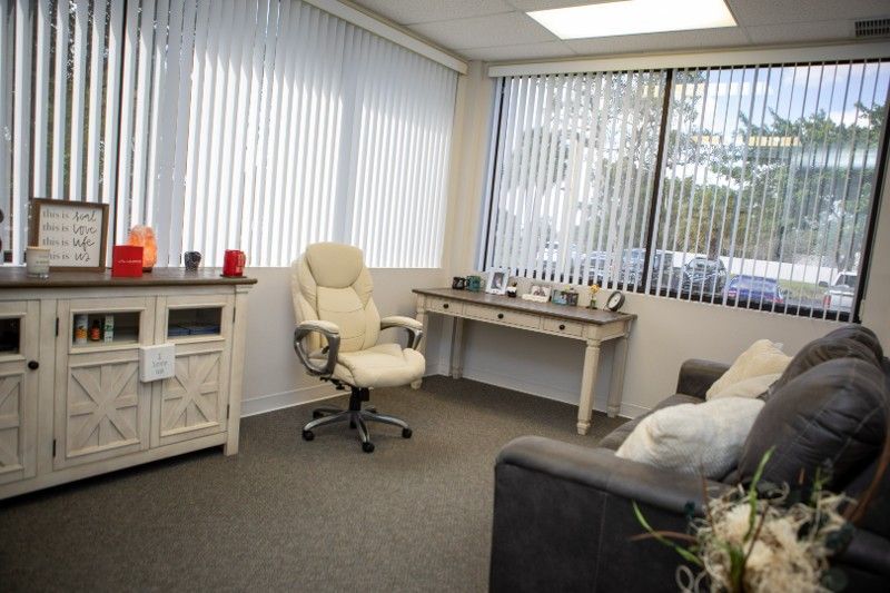 An office with a couch , desk , chair and blinds.