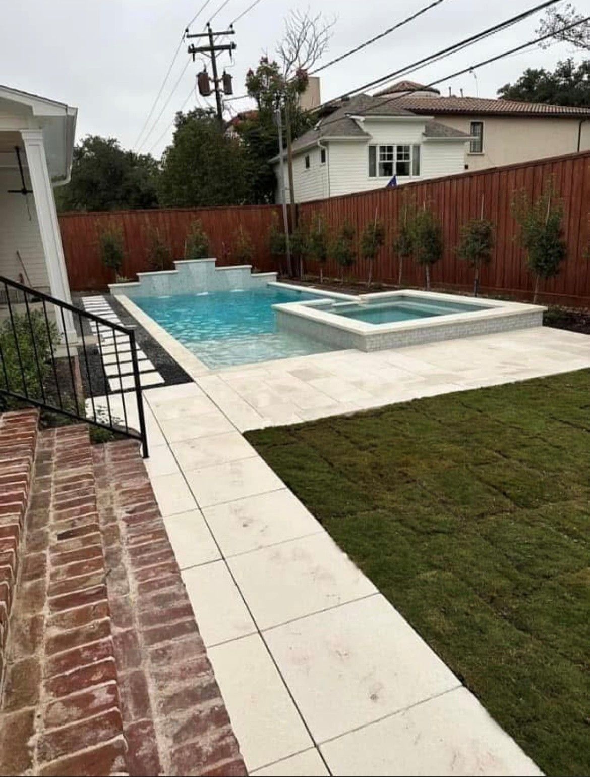 A large swimming pool is in the backyard of a house.