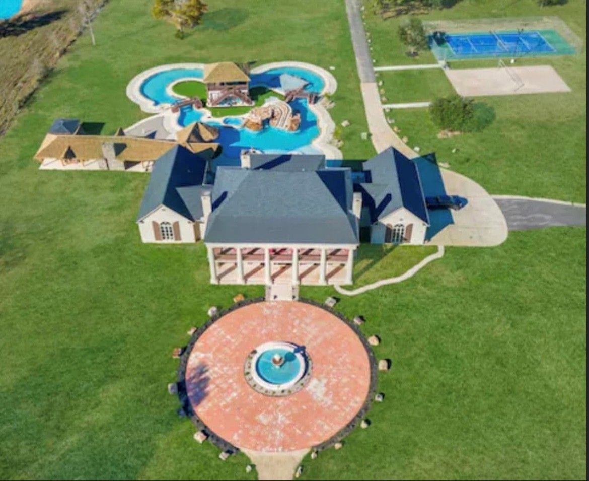 An aerial view of a large house with a fountain in the middle