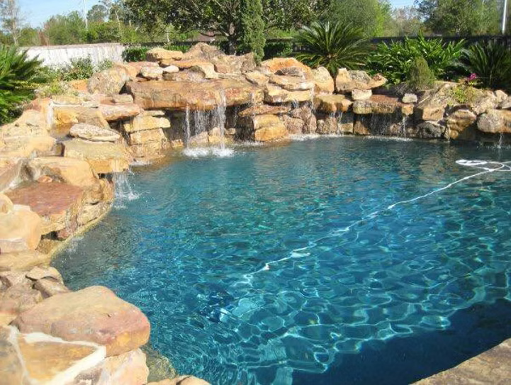 A large swimming pool with a waterfall in the middle