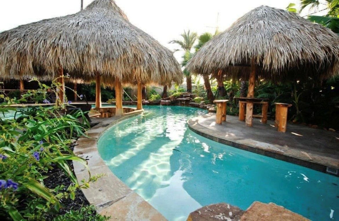 A large swimming pool with thatched huts around it