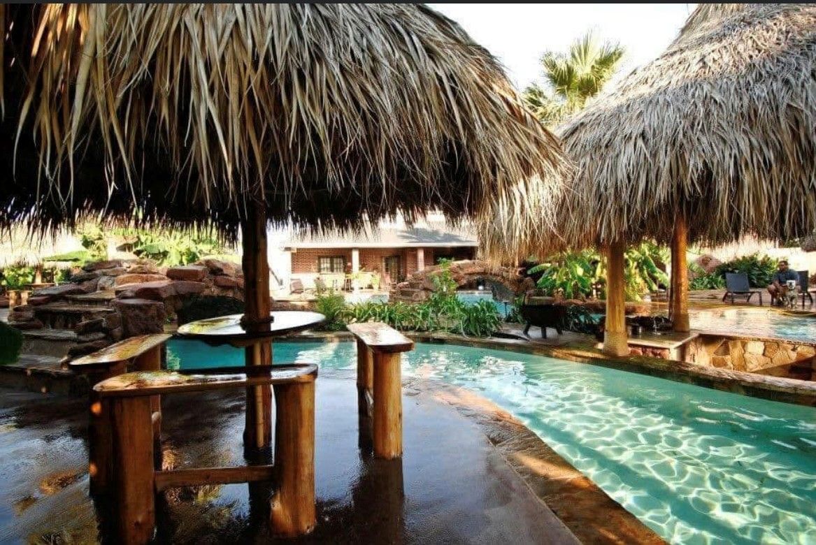 A swimming pool with thatched umbrellas and tables