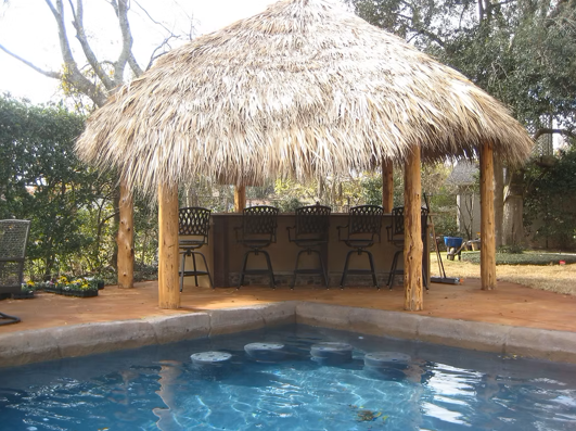A swimming pool with a thatched hut over it