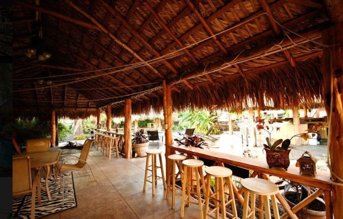 A thatched roofed room with tables and stools