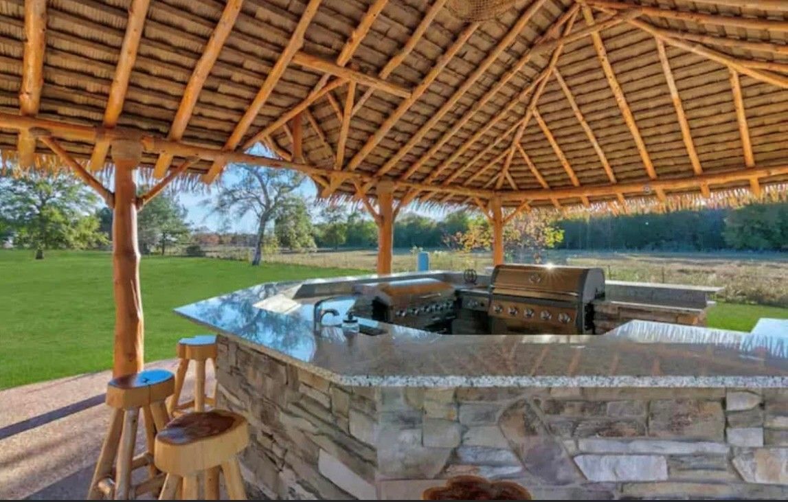 A gazebo with a grill and a bar underneath it.