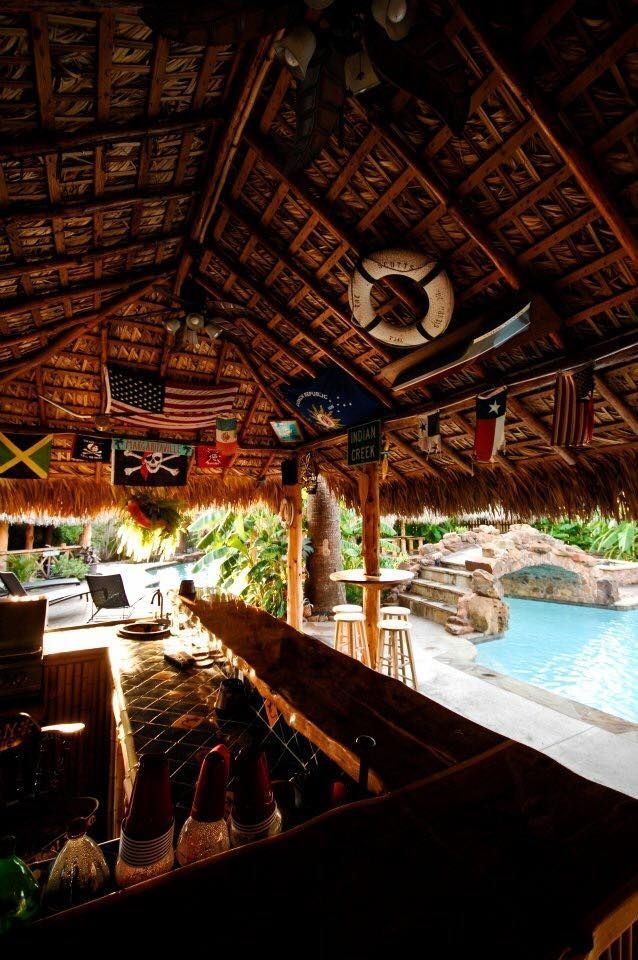 A bar with a thatched roof and a pool in the background