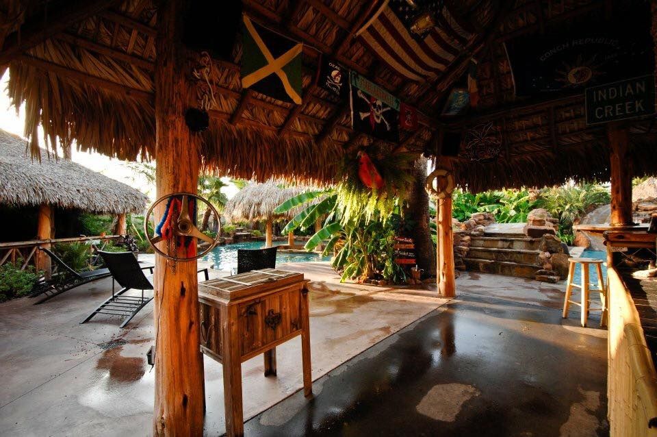 A thatched roofed area with a cooler underneath it