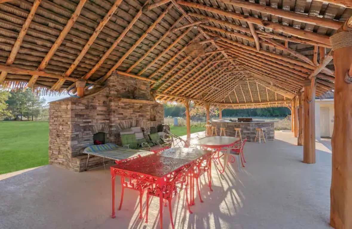 A covered patio with a table and chairs under a wooden roof.