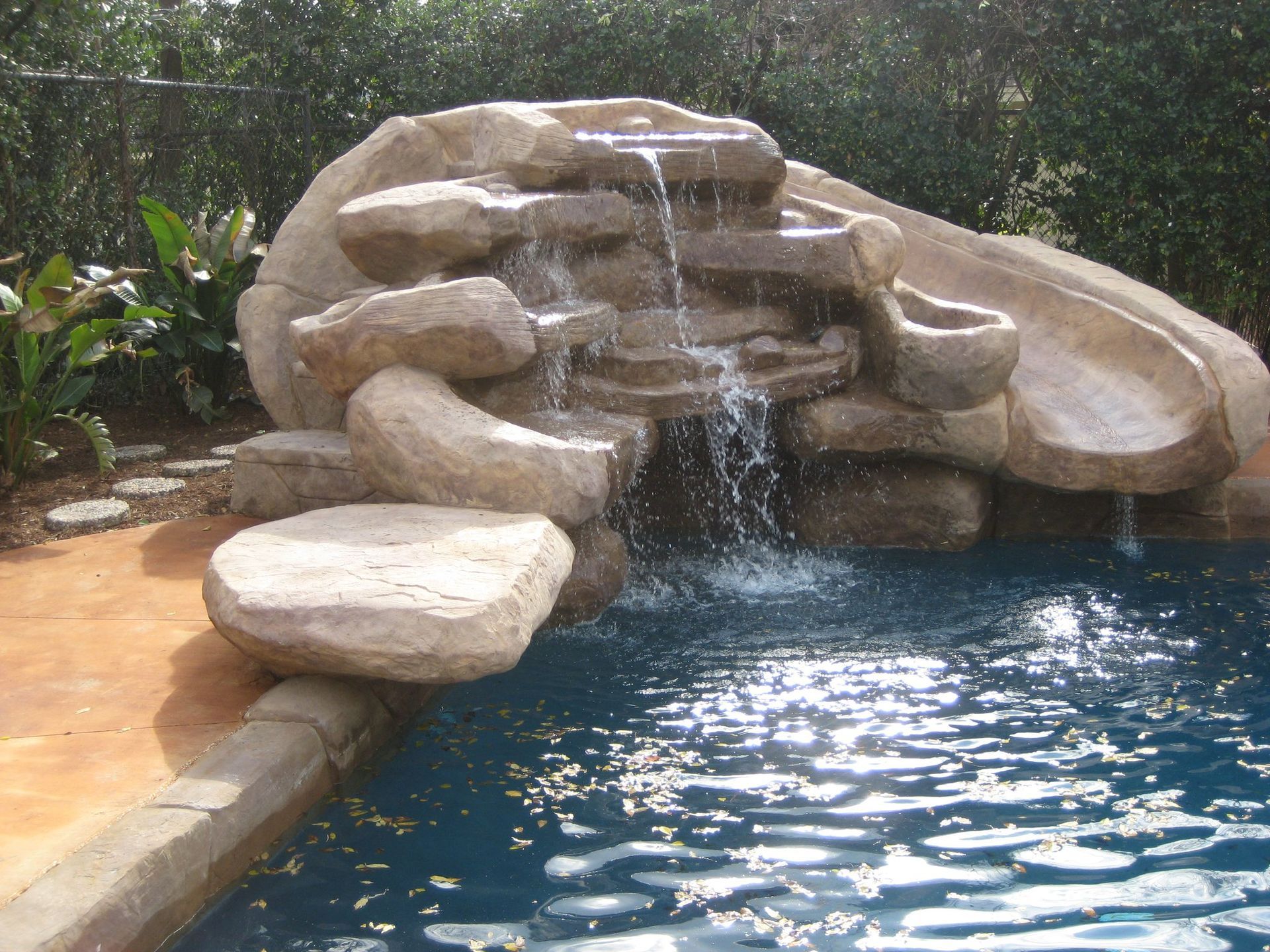 A swimming pool with a waterfall and a slide