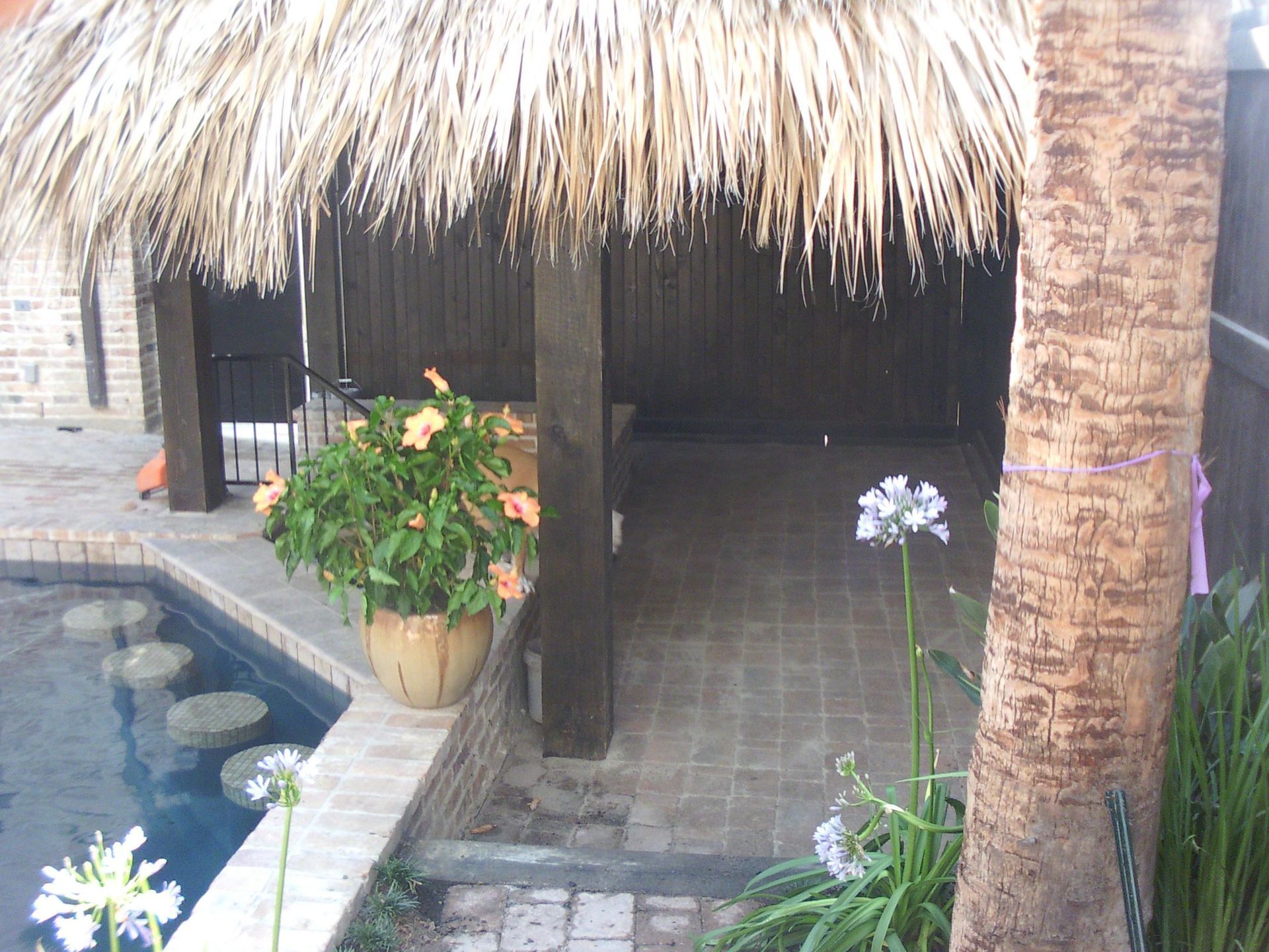 A thatched hut with flowers and a pool in the background