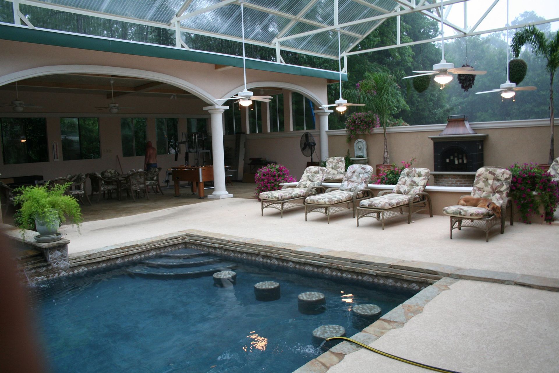 A large swimming pool surrounded by chairs and a fireplace