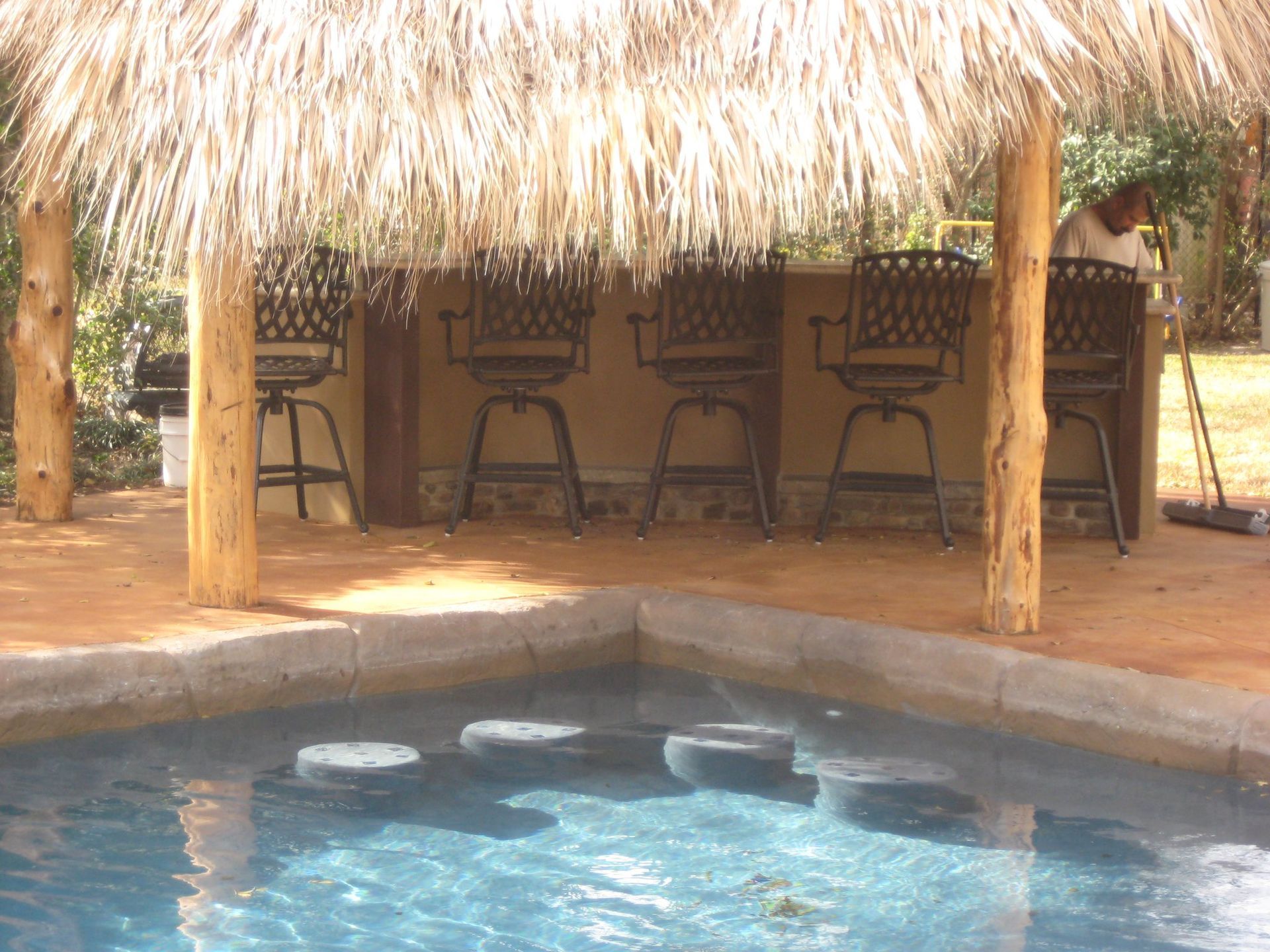 A swimming pool with a thatched bar and chairs