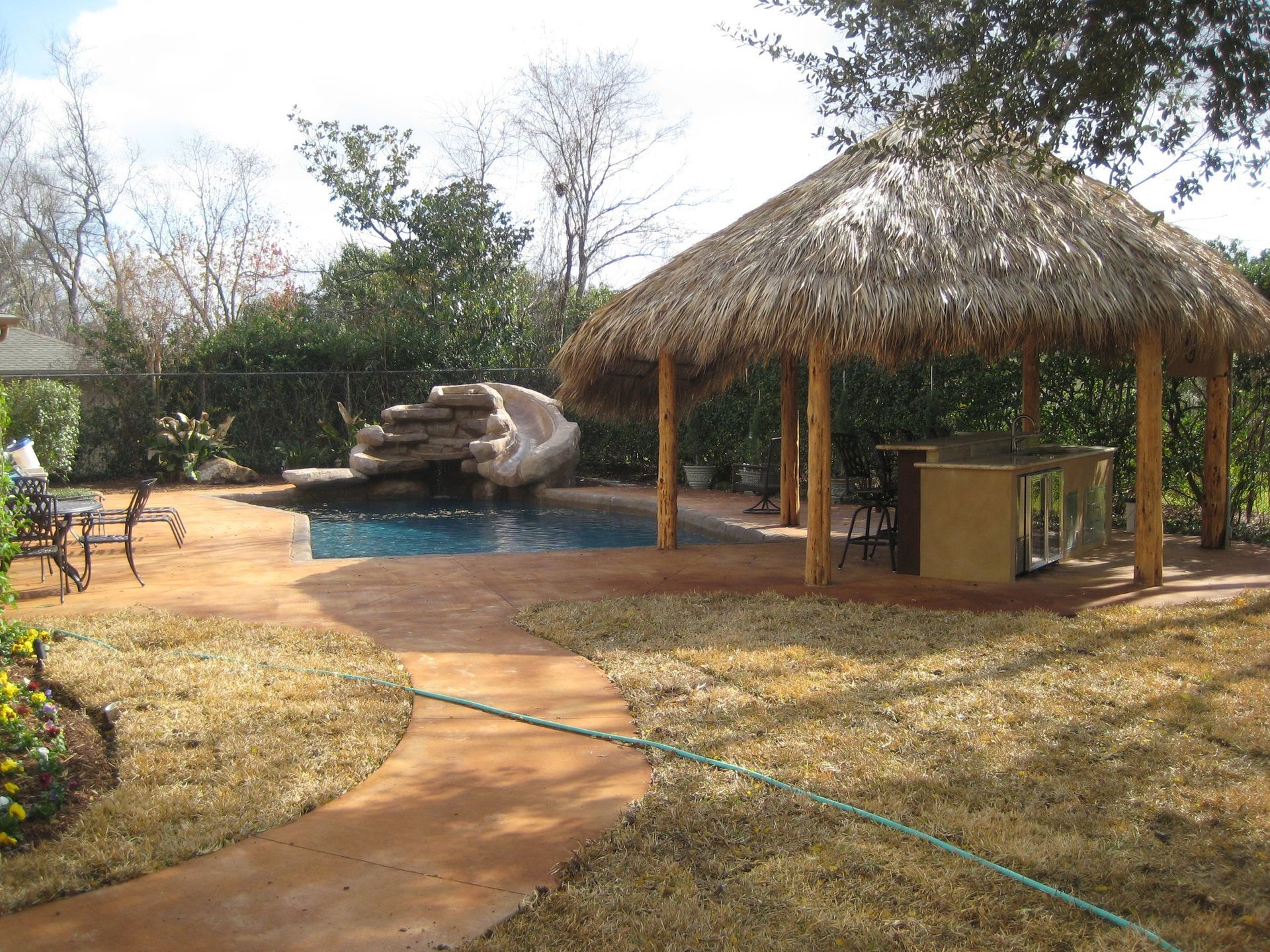 A thatched gazebo with a pool in the background