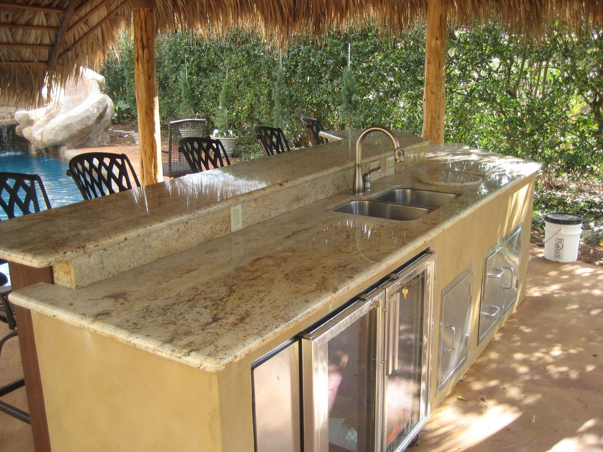 A kitchen with two sinks and a refrigerator under a thatched roof