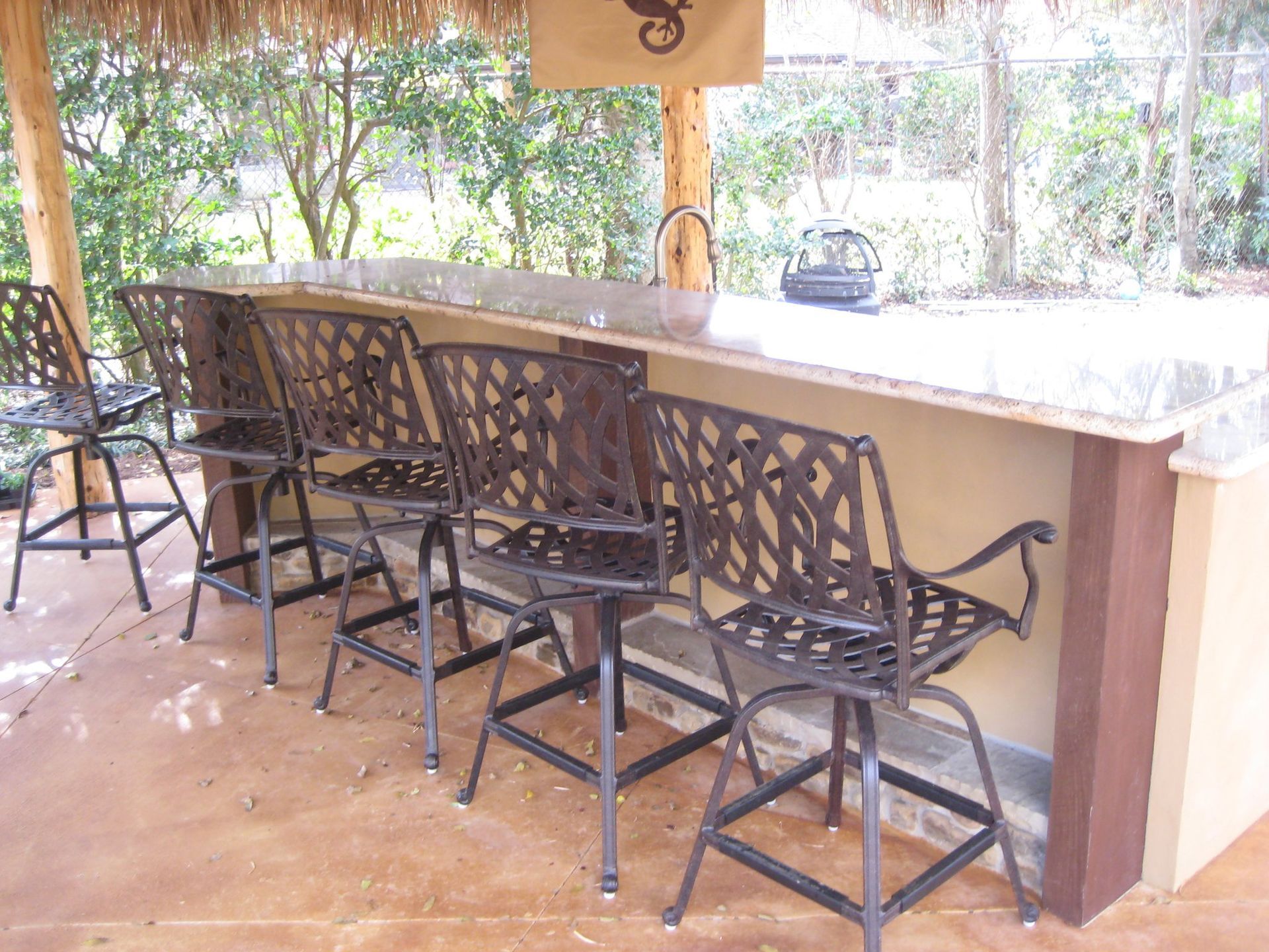 A row of chairs sitting next to a bar under a thatched roof.