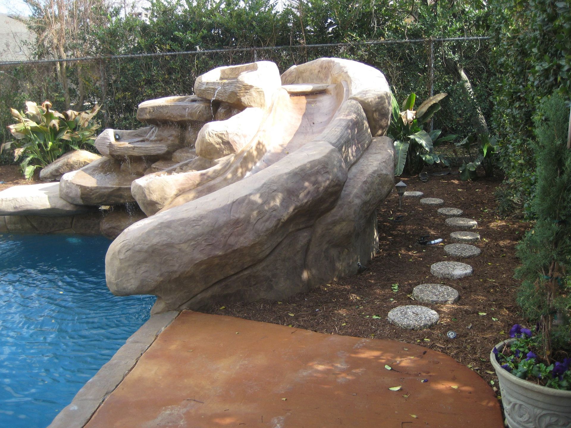 A large rock slide is next to a swimming pool