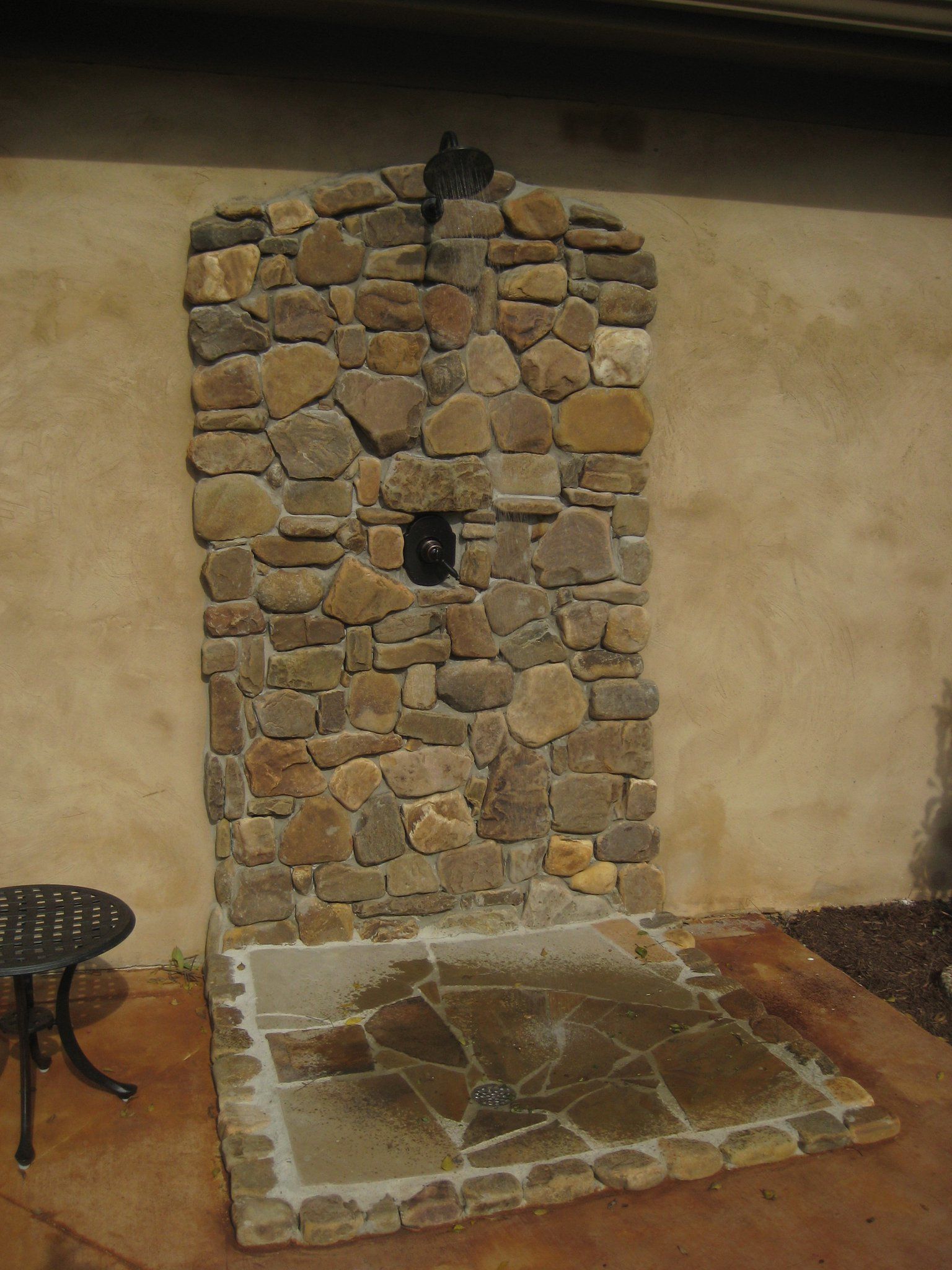 A stone shower is built into the side of a building