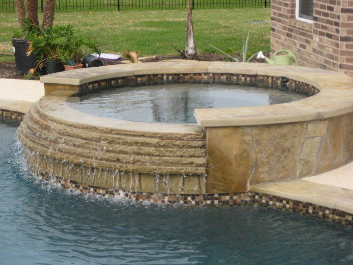 A hot tub with a waterfall in the middle of a pool
