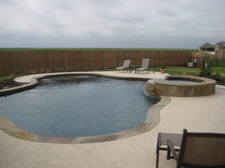 A large swimming pool surrounded by chairs and a fence
