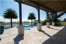There is a large swimming pool in the backyard with palm trees.