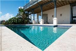 There is a large swimming pool in front of a house.