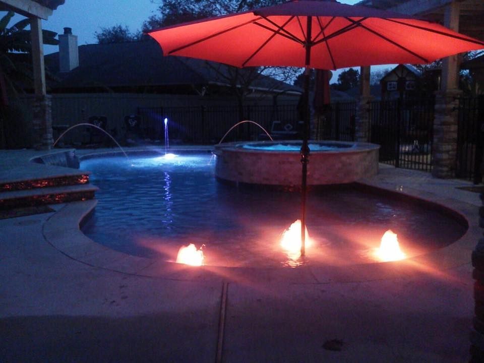 A red umbrella is sitting in front of a pool at night