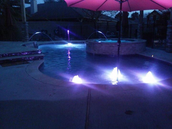 A swimming pool with purple lights and a pink umbrella