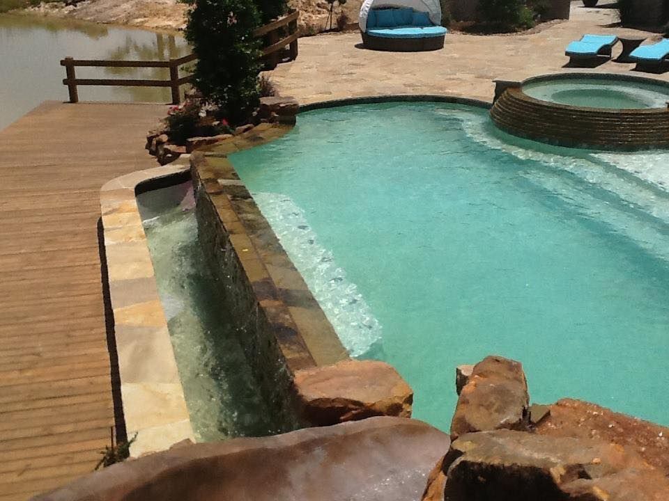 A large swimming pool surrounded by rocks and a wooden deck