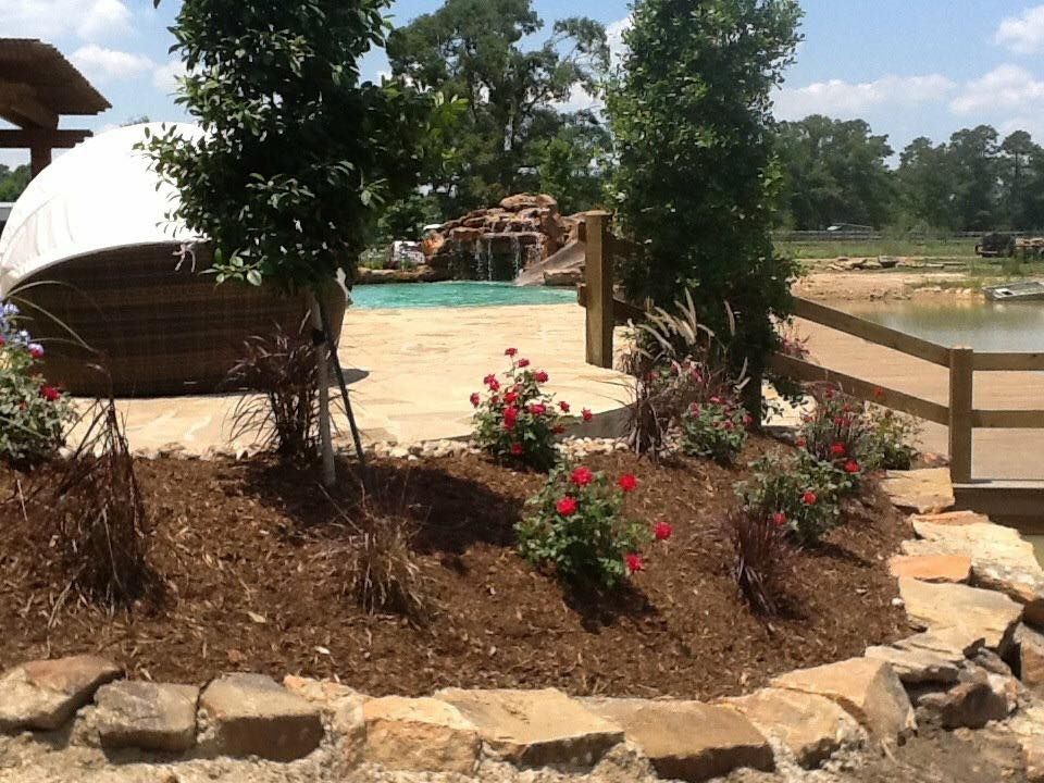 A swimming pool is surrounded by rocks and flowers