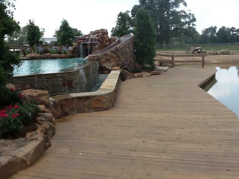 A wooden walkway leading to a pool with a waterfall