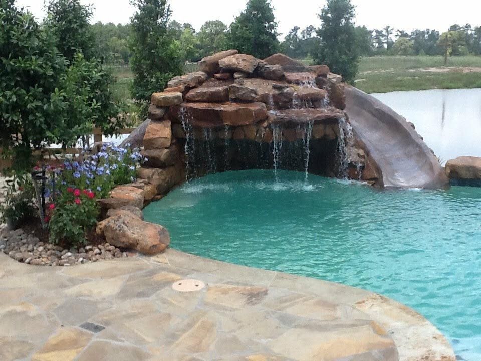 A swimming pool with a waterfall and a slide