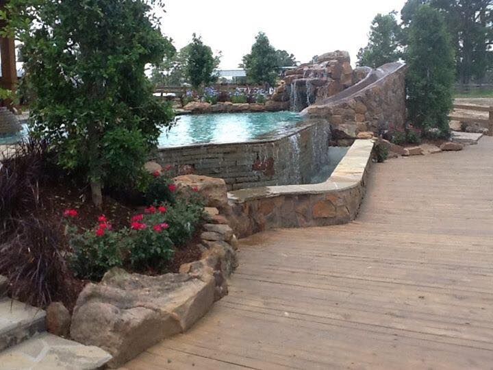 A wooden walkway leading to a pool with a waterfall