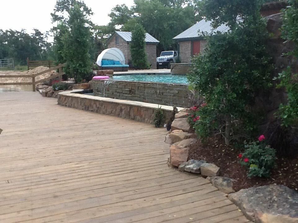 A wooden deck with a swimming pool in the background
